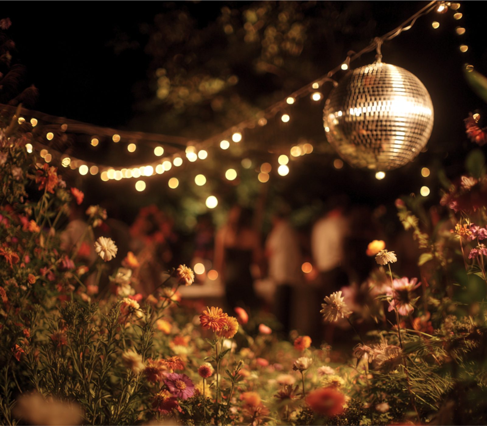 String lights, a mirrored ball and wildflowers in the courtyard at dusk